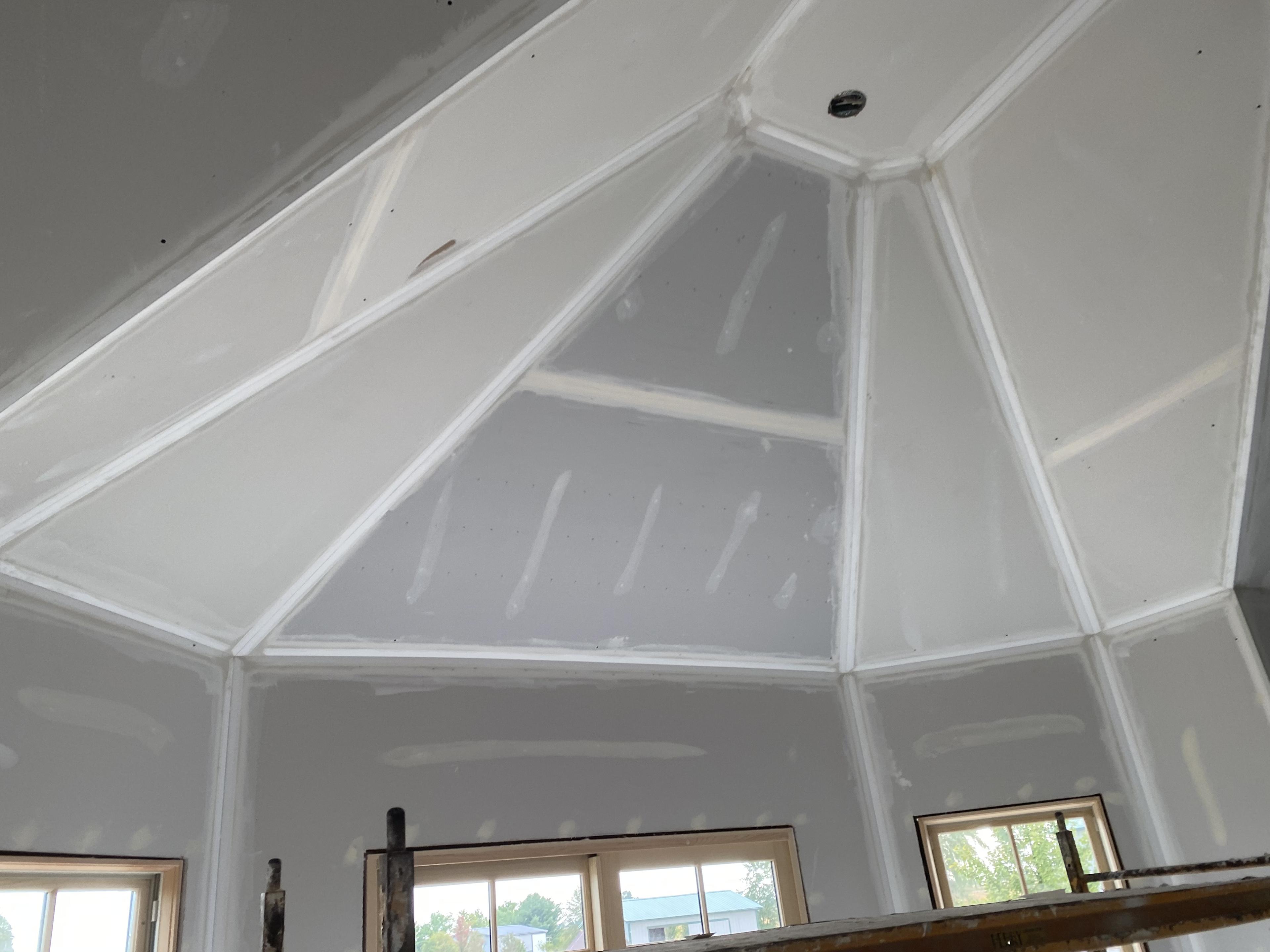 A ceiling with many angled slants, after drywall work.