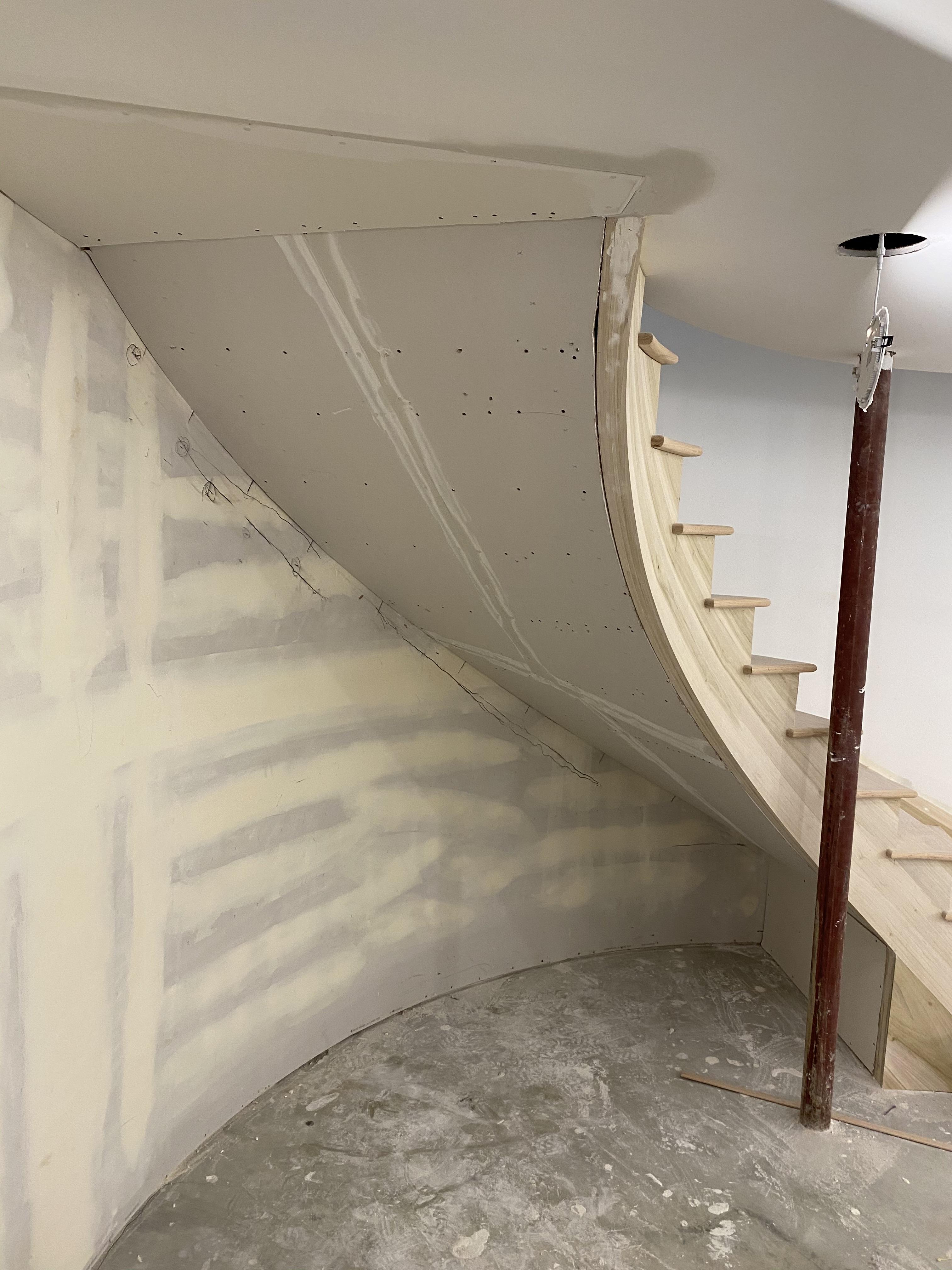 The underside of a spiral staircase, after drywall work.